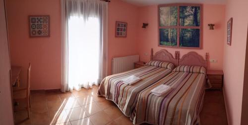 a bedroom with a bed and a window at Hostal La Vega in Peralejos