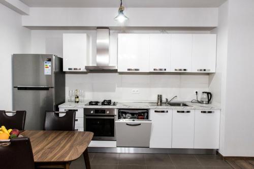 a kitchen with white cabinets and a wooden table at 7th HEAVEN Apartment in Central Tbilisi in Tbilisi City