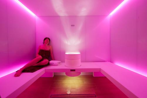 a woman sitting in a pink room with a light at Chalet Vites Mountain Hotel in Canazei