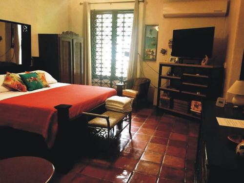 a bedroom with a bed with a red blanket and a television at Villa Vassallo in Ponce