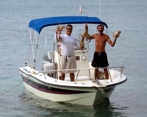 two men standing on a boat holding up lobsters at Villa Vassallo in Ponce