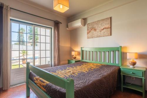 アルブフェイラにあるVilla Rato by Gabi Miguelのベッドルーム(緑のベッド1台、窓付)