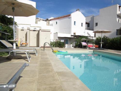 uma piscina com um guarda-sol ao lado de um edifício em La Corte dei Colori em Spongano