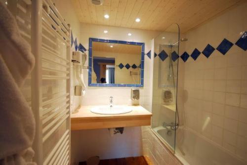 a bathroom with a sink and a shower and a mirror at Hotel Le Monal in Sainte-Foy-Tarentaise