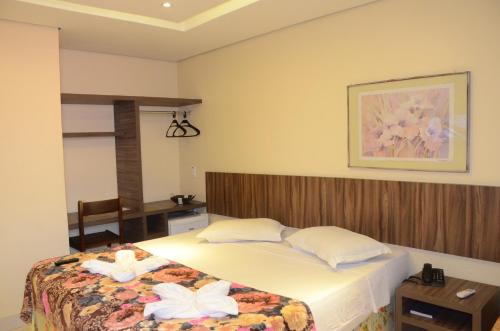 a bedroom with a bed with two white flowers on it at Ara Mar Praia Hotel in Fortaleza