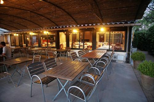 un patio con mesas de madera y sillas en un restaurante en Logis Auberge Cigaloise en Saint-Hippolyte-du-Fort