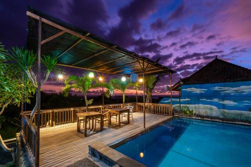 a deck with a dining table and a swimming pool at night at Sedok Jineng Villa Lembongan in Nusa Lembongan
