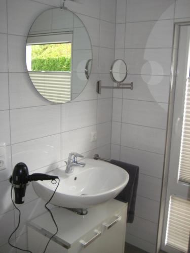 uma casa de banho branca com um lavatório e um espelho em City-Apartment Rietberg em Rietberg