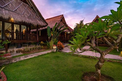 a resort with a grass yard and a building at Sedok Jineng Villa Lembongan in Nusa Lembongan
