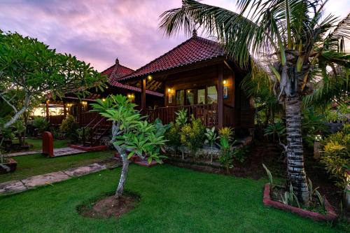 a house with a palm tree in front of it at Sedok Jineng Villa Lembongan in Nusa Lembongan