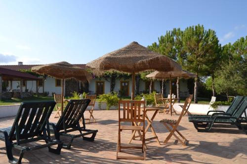 a group of chairs and tables with straw umbrellas at Casa de Campo Vale do Asno in Altura