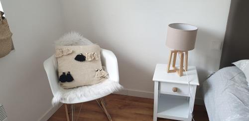 a white chair with a pillow on it next to a bed at Gîtes Les 3 Tours 2 in Carcassonne