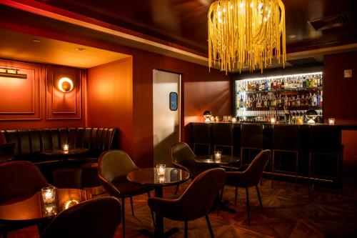 een restaurant met tafels en een bar met een kroonluchter bij Hotel 32 32 in New York
