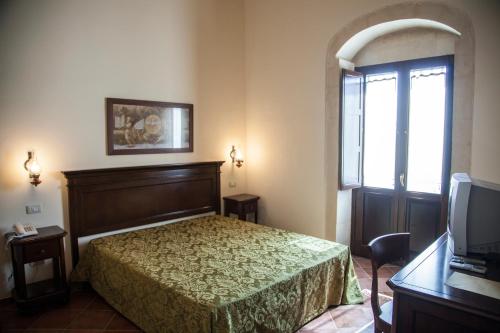 a hotel room with a bed and a television at Feudo Bauly in Palazzolo Acreide