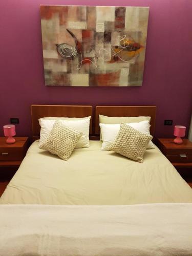 un letto con lenzuola e cuscini bianchi in una camera da letto di Residenza Annalisa a Torri di Quartesolo