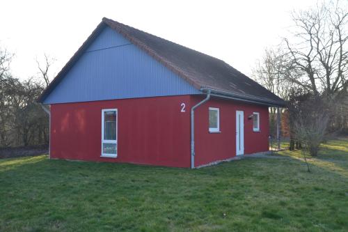 eine rote Scheune mit blauem Dach auf einem Feld in der Unterkunft Ostseehotel Klützer Winkel in Hohen Schönberg