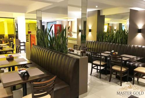 uma sala de jantar com mesas e cadeiras num restaurante em Master Gold Hotel Express em Cascavel
