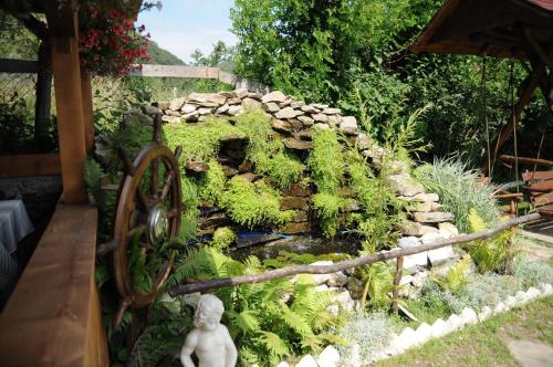 a garden with a stone waterfall and a statue at Pensiunea Domnescu in Sălişte
