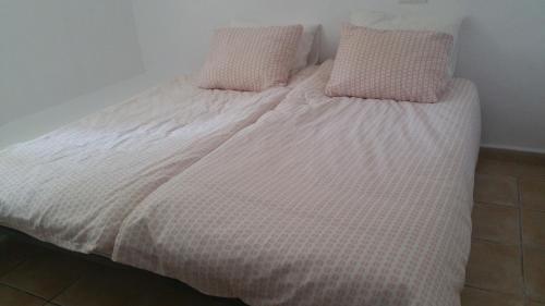 a white bed with two pink pillows on it at Casa Fleuri in La Nucía