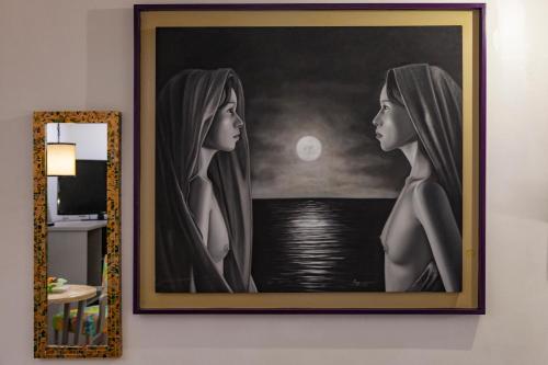 a painting of two women hanging on a wall at Mestizo Gallery in Tulum