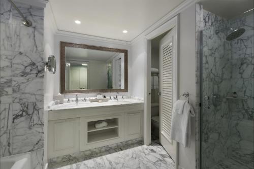 a bathroom with a sink and a mirror and a shower at Fairmont Orchid Gold Experience in Waikoloa