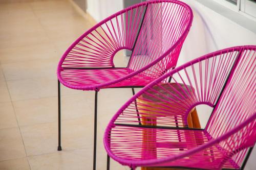 a pair of pink chairs sitting next to a wall at Mestizo Gallery in Tulum