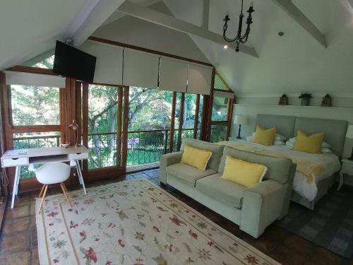 a bedroom with a bed and a couch and a desk at Aan De Vliet Guest House in Stellenbosch