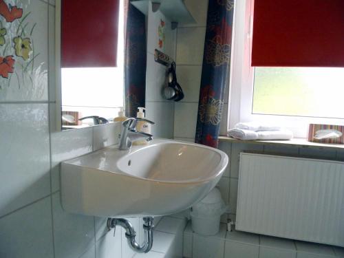 a white sink in a bathroom with two windows at Strandnest Büsum in Büsum