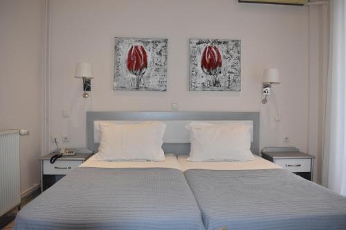 a bed in a bedroom with two paintings on the wall at Marinis Boutique Rooms in Iraklitsa
