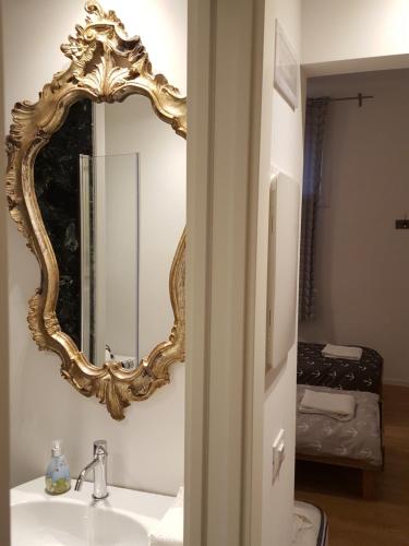 ein Badezimmer mit einem goldenen Spiegel über einem Waschbecken in der Unterkunft Casa Barzizza in Venedig