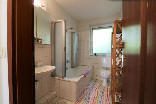 a bathroom with a tub and a sink and a toilet at Ferienwohnung Schenefelder Drift in Stadt Schenefeld