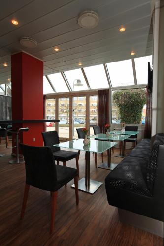 a dining room with a glass table and chairs at Hotel Svendborg in Svendborg