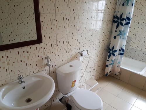 a bathroom with a white toilet and a sink at Hotel Embassy in Nairobi