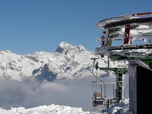 a ski lift in front of a snow covered mountain at Snežak (Snowman) 2 in Bohinj