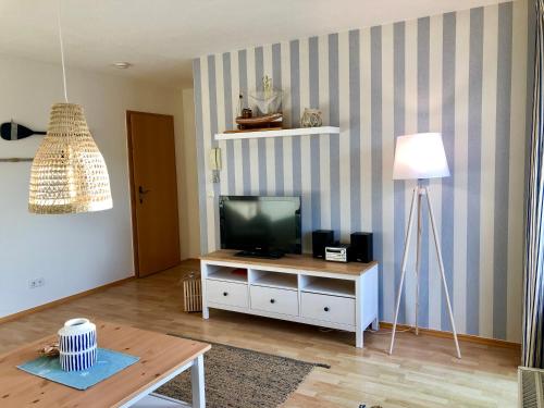 Ferienwohnung preiswert und strandnah في فارنمونده: غرفة معيشة مع تلفزيون وطاولة
