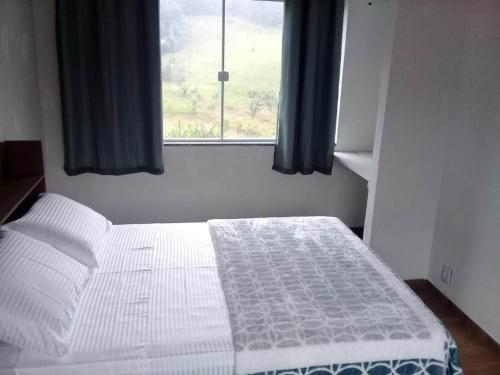 a white bed in a room with a window at Chalé duplex reformado - Fazenda Cantinho in Teresópolis