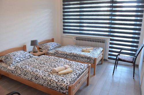 two twin beds in a room with a window at Prenoćište M&A in Laktaši