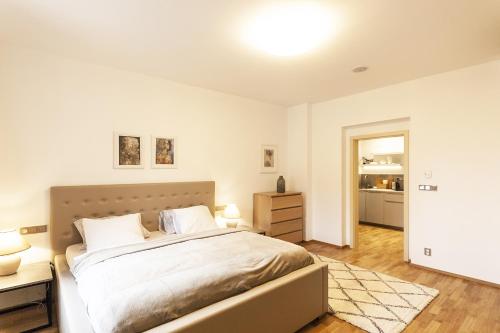 a white bedroom with a bed and a night stand at Prague Expat House in Prague