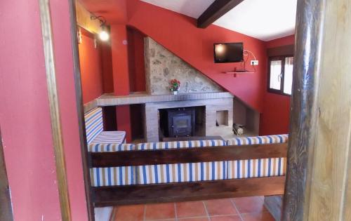 a living room with a fireplace and red walls at Fuente Del Gamellon in Buenache de la Sierra