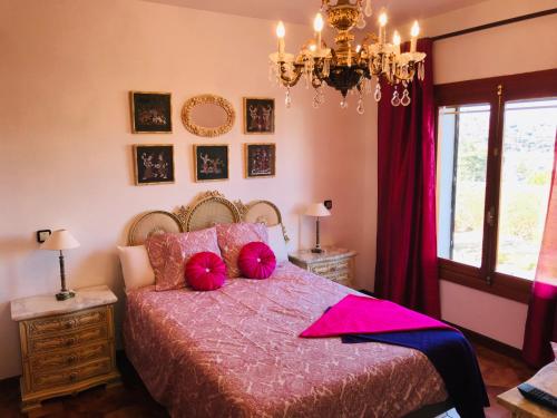 a bedroom with a bed with pink pillows and a chandelier at La Aldea in Aldea del Fresno