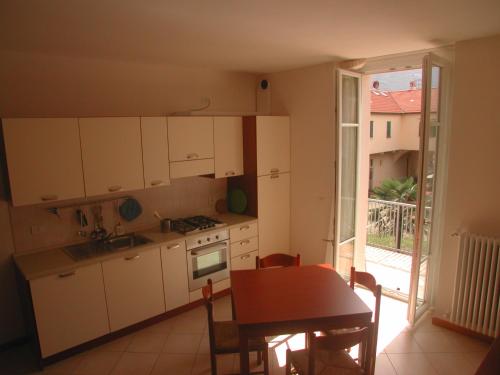 una cucina con armadi bianchi, tavolo e finestra di "Il Terrazzo" Apartment a Colico