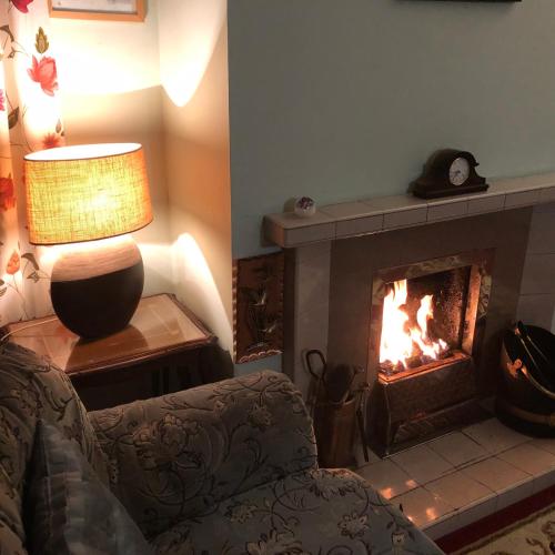 a living room with a fireplace with a chair and a lamp at Balmore in Dunvegan