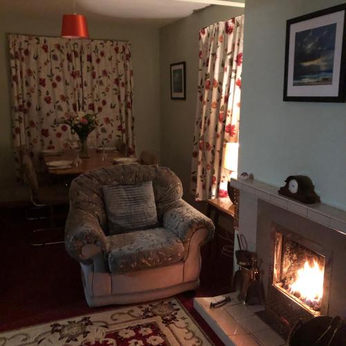 a living room with a chair and a fireplace at Balmore in Dunvegan