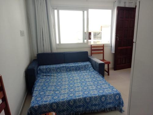 um quarto com uma cama azul e uma janela em Apartamentos Juliel em Morro de São Paulo