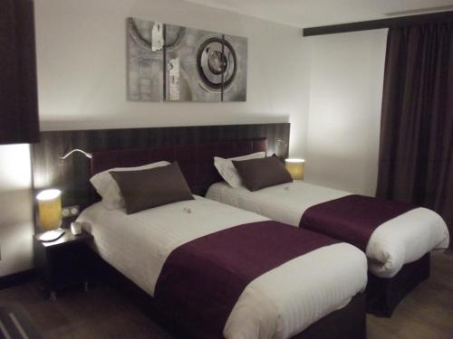 two beds in a hotel room with two beds at Le Domaine des Oliviers in Pierrelatte