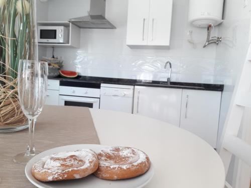 two donuts on a plate on a table with a glass at Wonderful, 100 meters from the beach. in Can Picafort
