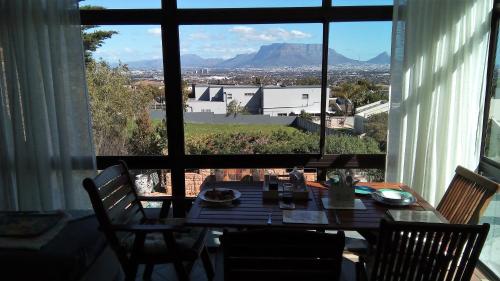 mesa de comedor con sillas y ventana grande en Ville la'Rina, en Ciudad del Cabo