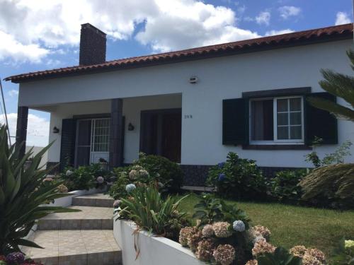 una casa blanca con persianas y plantas negras en Vivenda Garcia B&B, en Relva