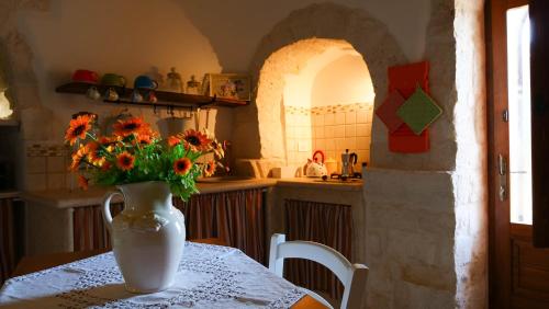 un jarrón de flores sobre una mesa en una cocina en Trulli Barsento, en Alberobello