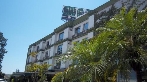 Canoas Parque Hotel في كانواس: مبنى أبيض طويل مع أشجار النخيل أمامه